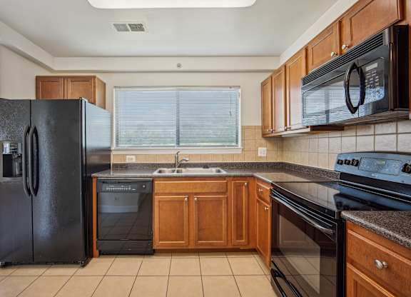 A kitchen with black appliances and wooden cabinets at Elme Bethesda, Bethesda, 20814