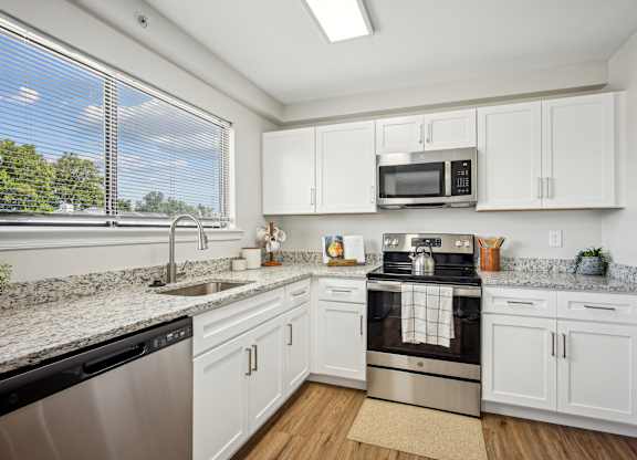 A kitchen with white cabinets and a black stove top oven at Elme Bethesda, Bethesda, 20814
