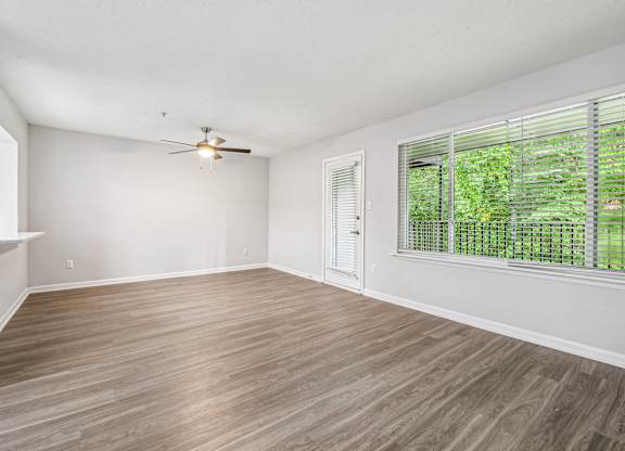 A room with a ceiling fan and a window with blinds.