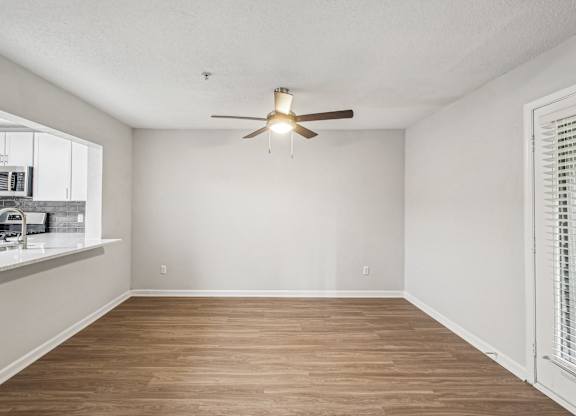 A room with a ceiling fan and wooden flooring.