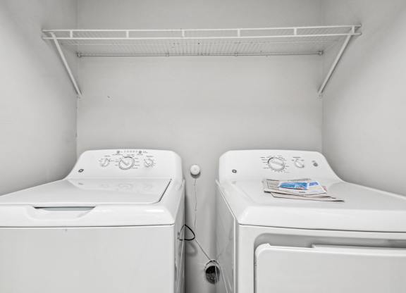Two white washing machines in a small laundry room.