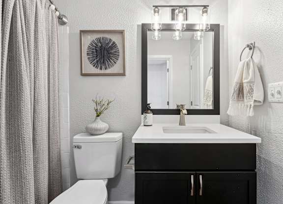 A bathroom with a white toilet, a sink, a mirror, and a plant at Elme Druid Hills, Atlanta, Georgia