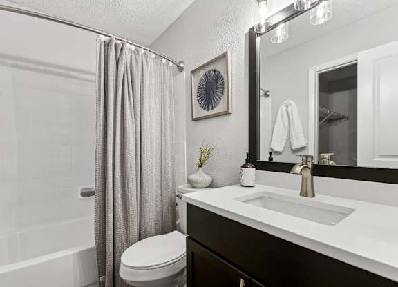 A bathroom with a white sink, toilet, and a shower with a grey curtain at Elme Druid Hills, Atlanta, Georgia