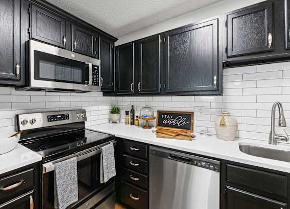 A kitchen with black cabinets and a white backsplash at Elme Druid Hills, Atlanta, Georgia