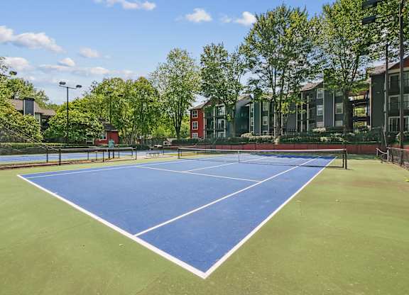 A tennis court surrounded by trees and buildings at Elme Druid Hills, Atlanta, Georgia