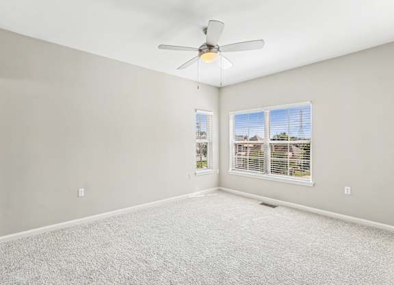 A room with a ceiling fan and carpeted floor.