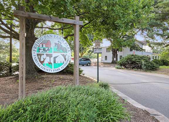 A sign for Frying Pan Farm Park is displayed in front of a tree.