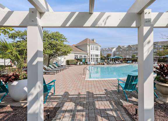 A pool surrounded by chairs and plants under a white pergola at Elme Dulles, Herndon, VA