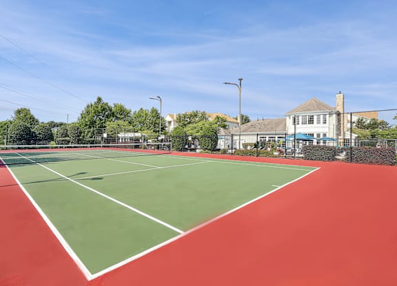 A tennis court with a red surface and white lines.