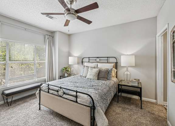 A bedroom with a bed, nightstand, and window.