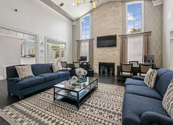 A living room with a blue couch and a glass coffee table.