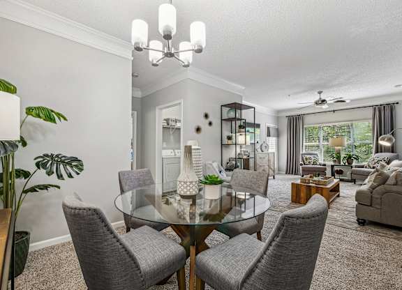 A modern dining room with a glass table and grey chairs.