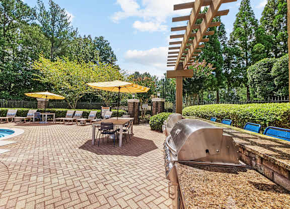 A patio with a table and chairs and a pool.