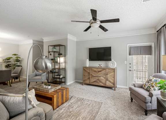 A living room with a grey couch, a wooden cabinet, and a TV on the wall.