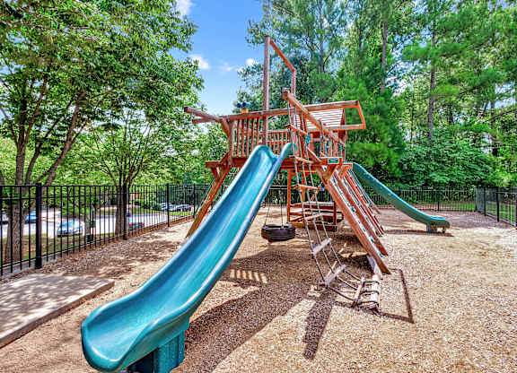 A playground with a green slide and a red wooden structure.