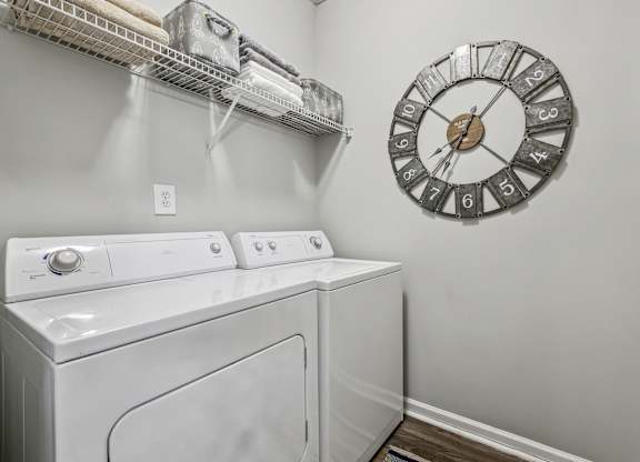 A laundry room with a washer and dryer and a clock on the wall.