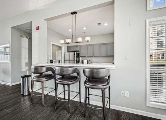 A kitchen with a bar area and three bar stools.