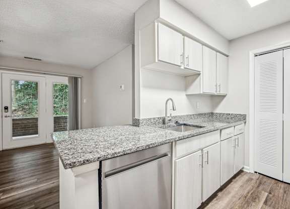 A kitchen with white cabinets and a granite countertop.