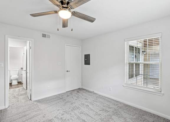 A room with a ceiling fan and a window with blinds.