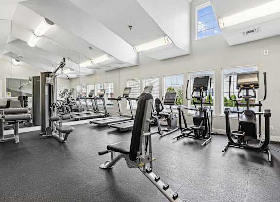 A spacious gym with various exercise equipment and a large mirror on the wall.