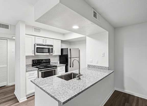 A kitchen with a granite countertop and stainless steel appliances.