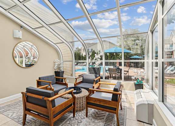 A sunroom with a glass ceiling and a round mirror on the wall.