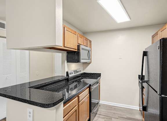 A kitchen with black countertops and a black refrigerator at Elme Leesburg, Virginia, 20176