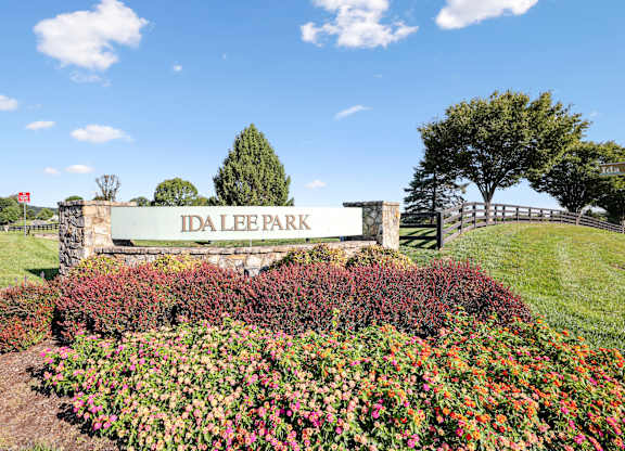A sign that says Ida Lee Park in front of a tree.