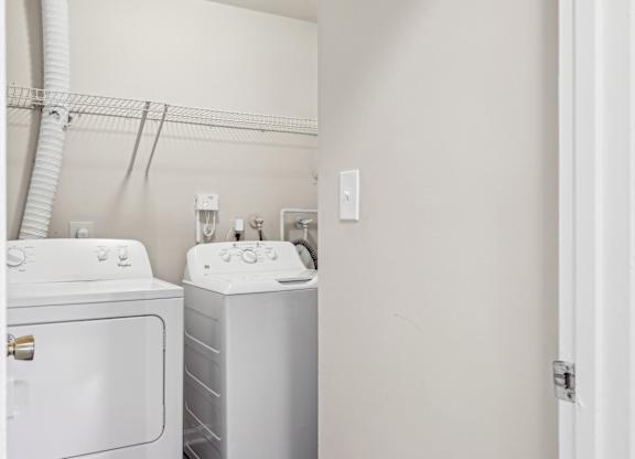 A white washing machine and dryer in a small laundry room at Elme Leesburg, Virginia, 20176