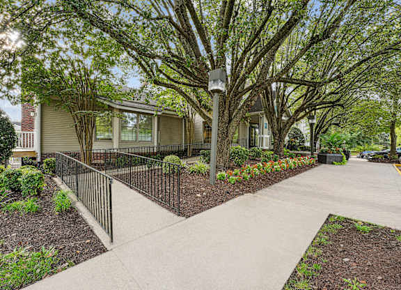 A tree-lined walkway leads to a building.