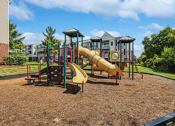 A playground with a yellow slide and a red and green structure.