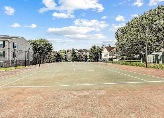 A tennis court surrounded by houses and trees.