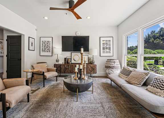 A living room with a large couch, a coffee table, and a ceiling fan  at Elme Marietta Apartments, Marietta, GA at Elme Marietta Apartments, Marietta, GA