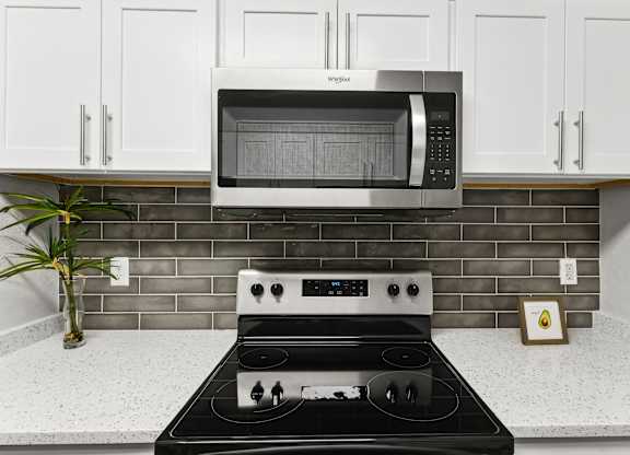 A modern kitchen with a black stove top and a white microwave above it.