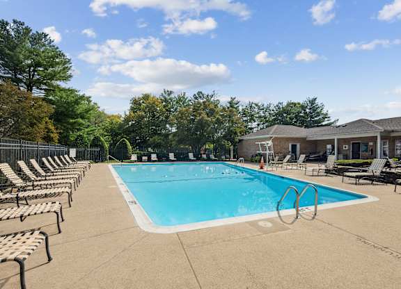 A large outdoor swimming pool surrounded by lounge chairs at Elme Watkins Mill, Gaithersburg