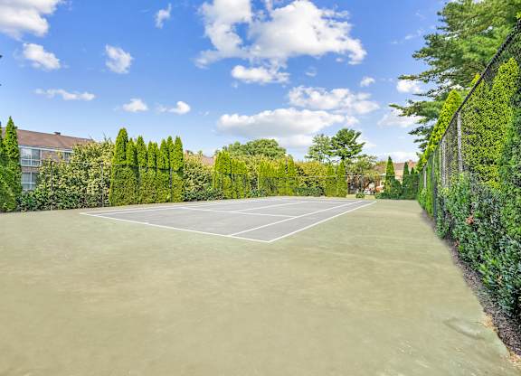 Tennis court surrounded by green trees and bushes at Elme Watkins Mill, Gaithersburg