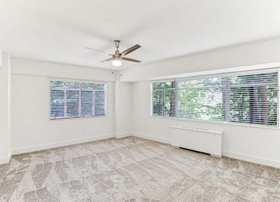 A room with a ceiling fan and a window with blinds.