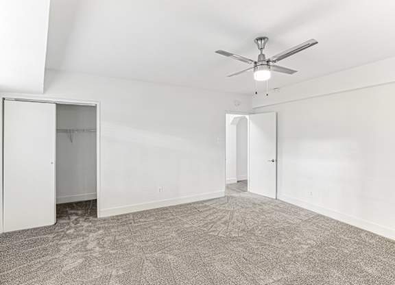 A room with a ceiling fan and carpeted floor.