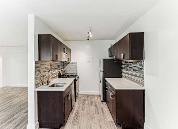 A kitchen with dark wood cabinets and a stone backsplash.