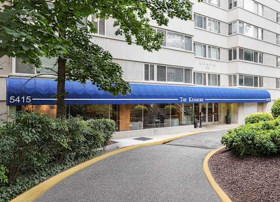 The entrance to The Kenmore apartment building is covered by a blue awning.