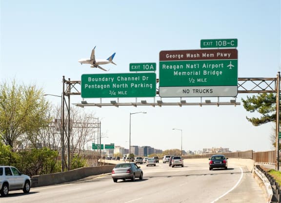 A plane flying over a highway with cars.