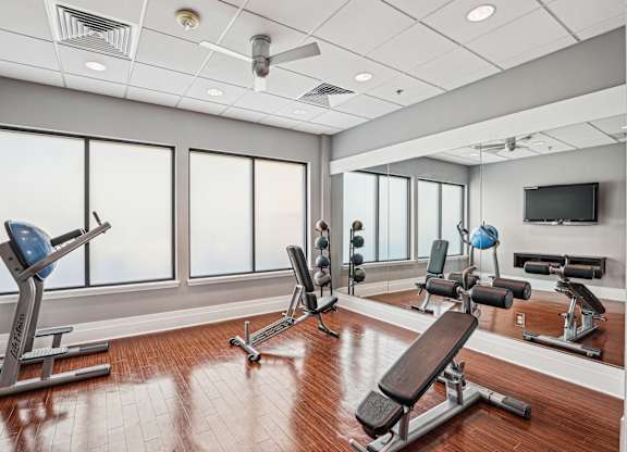 A gym with a variety of equipment including a bench press, a squat rack, and a barbell  at The Paramount, Arlington, Virginia