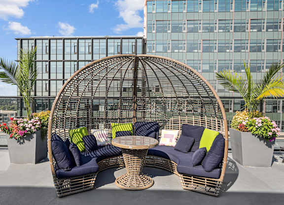 A wicker sofa with cushions and a table is set up on a balcony  at The Paramount, Arlington, Virginia