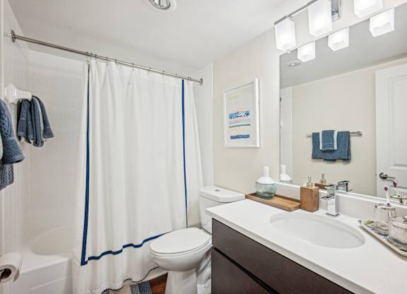 A white bathroom with a toilet, sink, and shower at Riverside Apartments, Alexandria, Virginia