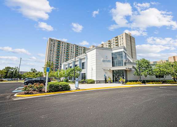 A modern building with a glass entrance and a parking lot in front at Riverside Apartments, Alexandria, Virginia