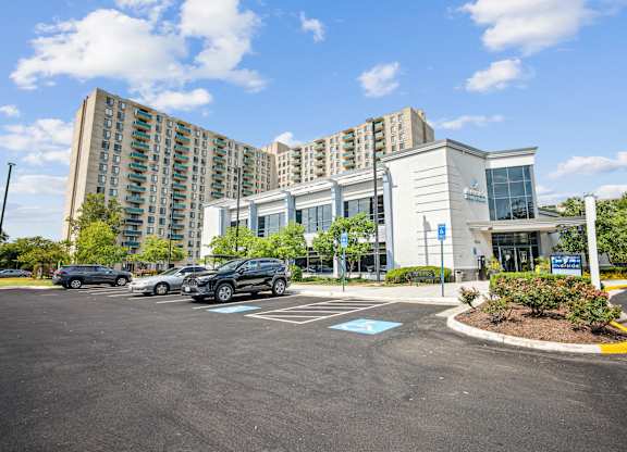 A parking lot in front of a building with a blue sign at Riverside Apartments, Alexandria, Virginia