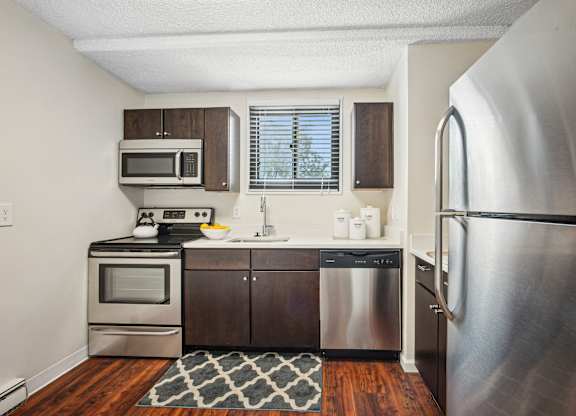 A kitchen with a stainless steel refrigerator, microwave, oven, and sink at Riverside Apartments, Alexandria, Virginia
