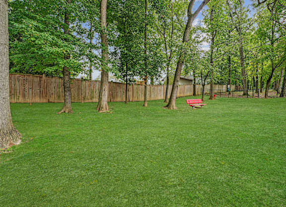 A backyard with a wooden fence and a red bench  at Roosevelt Towers, Falls Church, VA