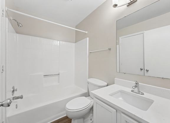 A white bathroom with a toilet, sink, and bathtub.