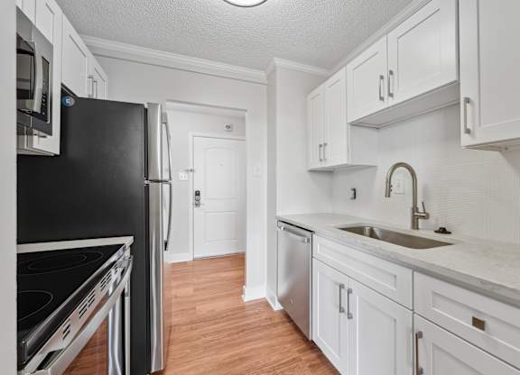 A kitchen with white cabinets and a black refrigerator  at Riverside Apartments, Alexandria, Virginia